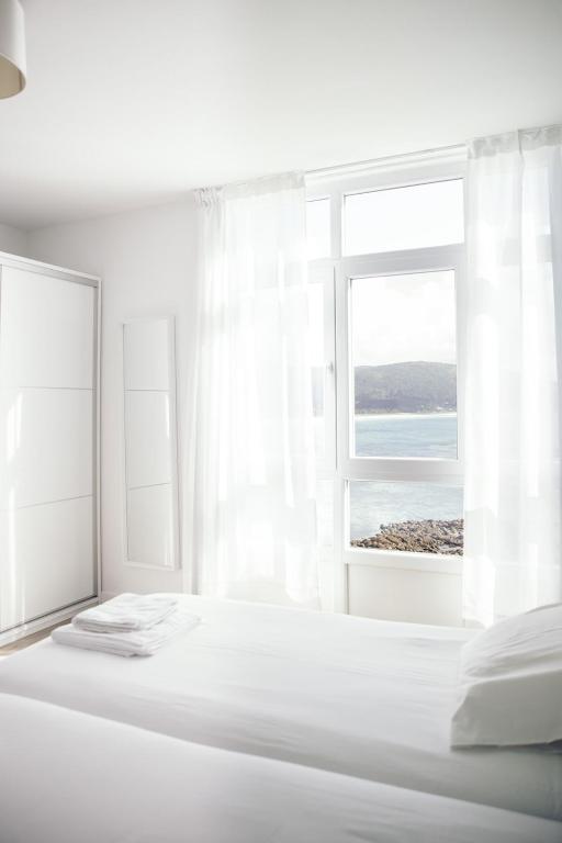 Dormitorio blanco con cama y ventana abierta en Hotel Mar de Fisterra, en Finisterre