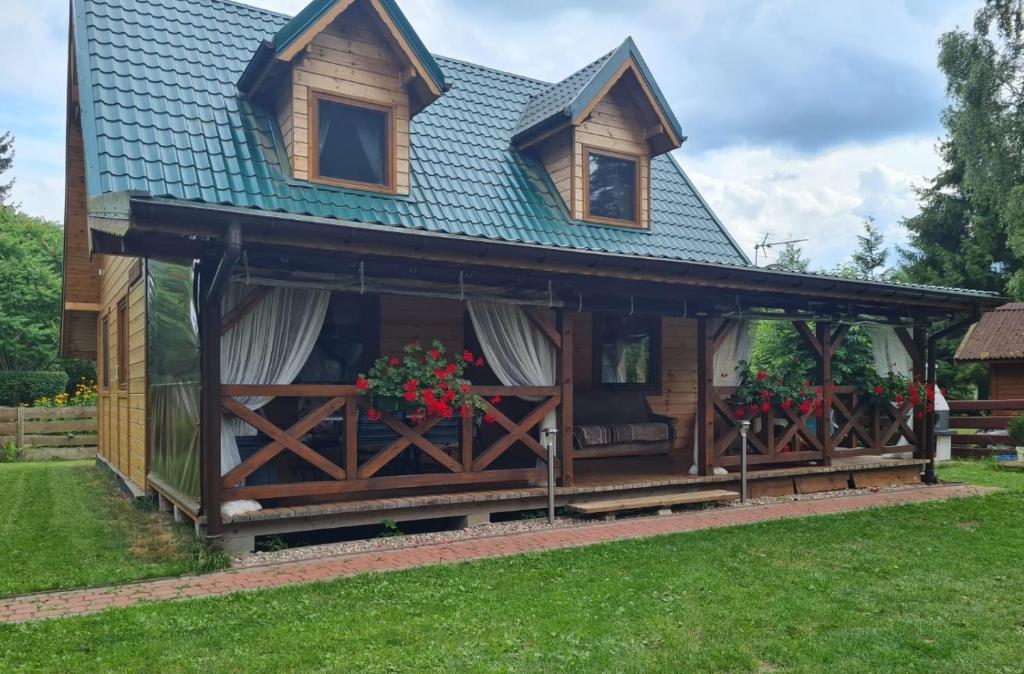 a log cabin with a porch and a blue roof at Ferienhaus "BASTEK2" am See mit Kamin & WLAN - Domek Letniskowy BASTEK in Pasym