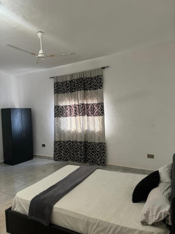 a bedroom with a bed and a window with a curtain at H&M Penthouse in Serekunda