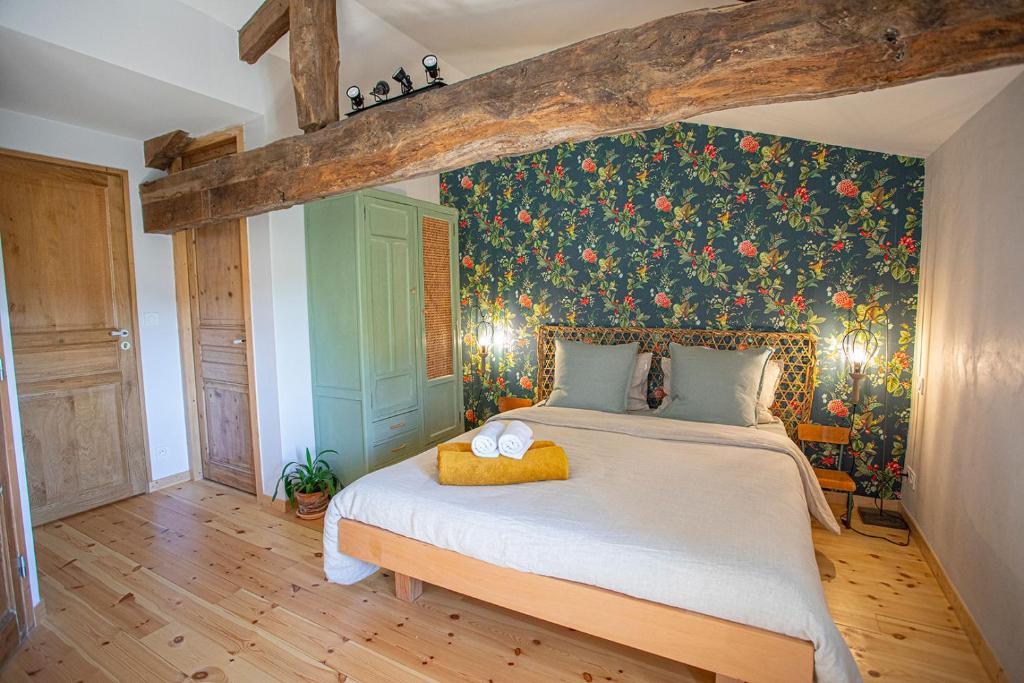 1 dormitorio con 1 cama grande y papel pintado con motivos florales en La Fée Capucine - Chambres et table d'hôtes - Espace bien-être et massages, en Saint-Galmier