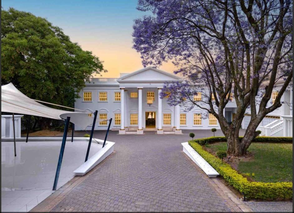 un grande edificio bianco con un albero di fronte di The White House a Johannesburg