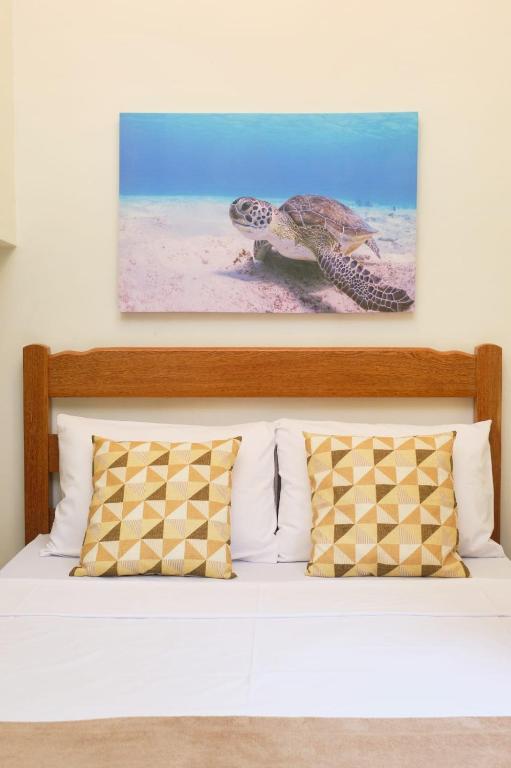 a picture of a turtle on the wall above a bed at Suítes VerdeMar Pereque-Açu in Ubatuba