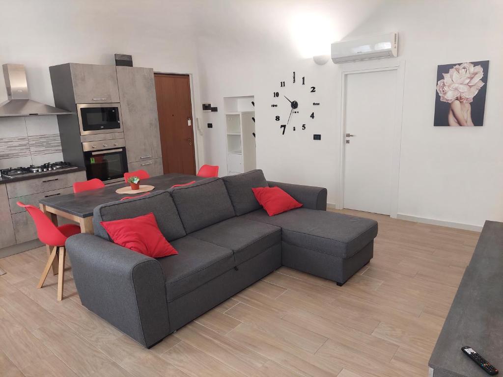 uma sala de estar com um sofá e uma mesa com almofadas vermelhas em Novi Outlet Apartment em Novi Ligure