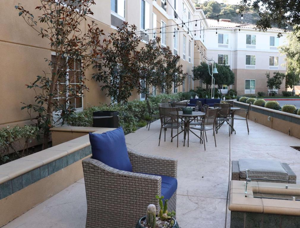 eine Terrasse mit Stühlen und Tischen in einem Gebäude in der Unterkunft Hilton Garden Inn Calabasas in Calabasas