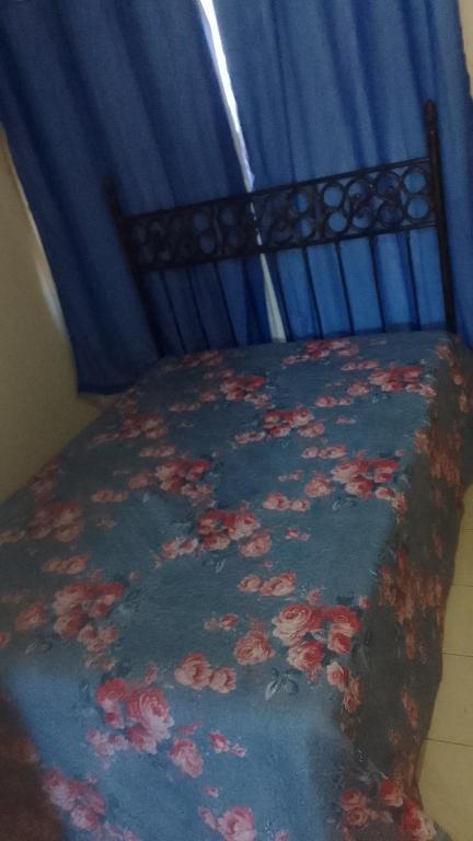 Una cama con una manta azul con flores. en Hospedaria Meu lar en Rio das Ostras