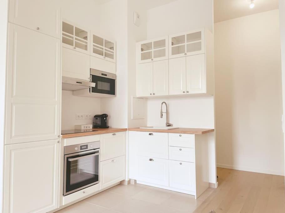 une cuisine blanche avec des armoires blanches et un évier dans l'établissement Superbe F3 calme-15 min deParis, à Clichy