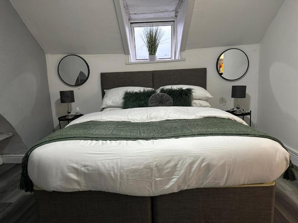 a bedroom with a large bed with two mirrors at Studio Flat Near City Centre in Newport