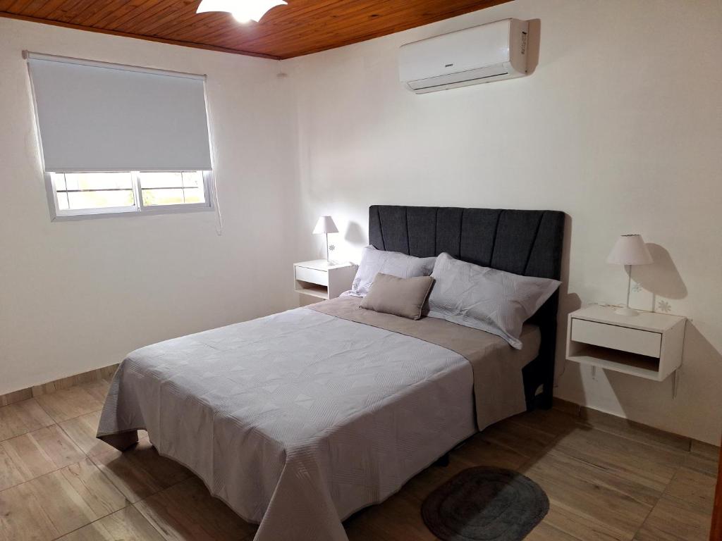 a white bedroom with a large bed and a window at Departamentos Muy Eugenia in San Rafael