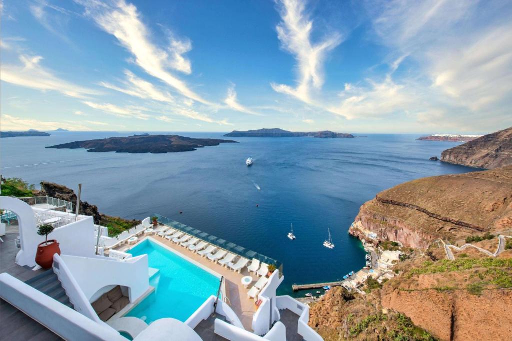 a villa with a pool and a view of the ocean at Athina Luxury Suites in Fira