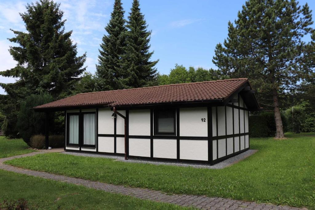 a small white and black building in a yard at Ferienhaus Robinson Am Krappennest 92 in Waldbrunn