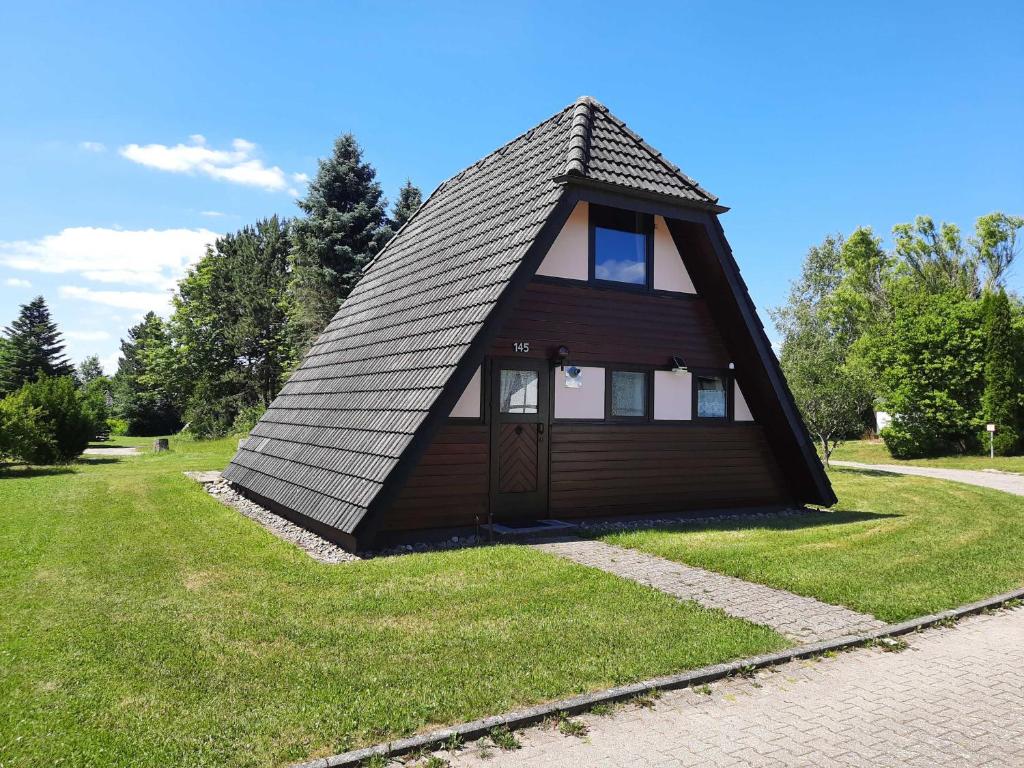 een klein huis met een gambrel dak op het gras bij Ferienhaus Winnetou Sonnenkreisel 145 in Waldbrunn