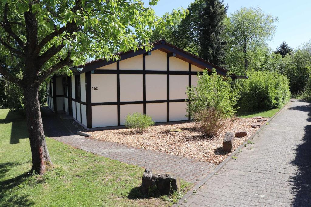 un garaje con un árbol y una acera en Ferienhaus Robinson Romantikpfad 162 en Waldbrunn