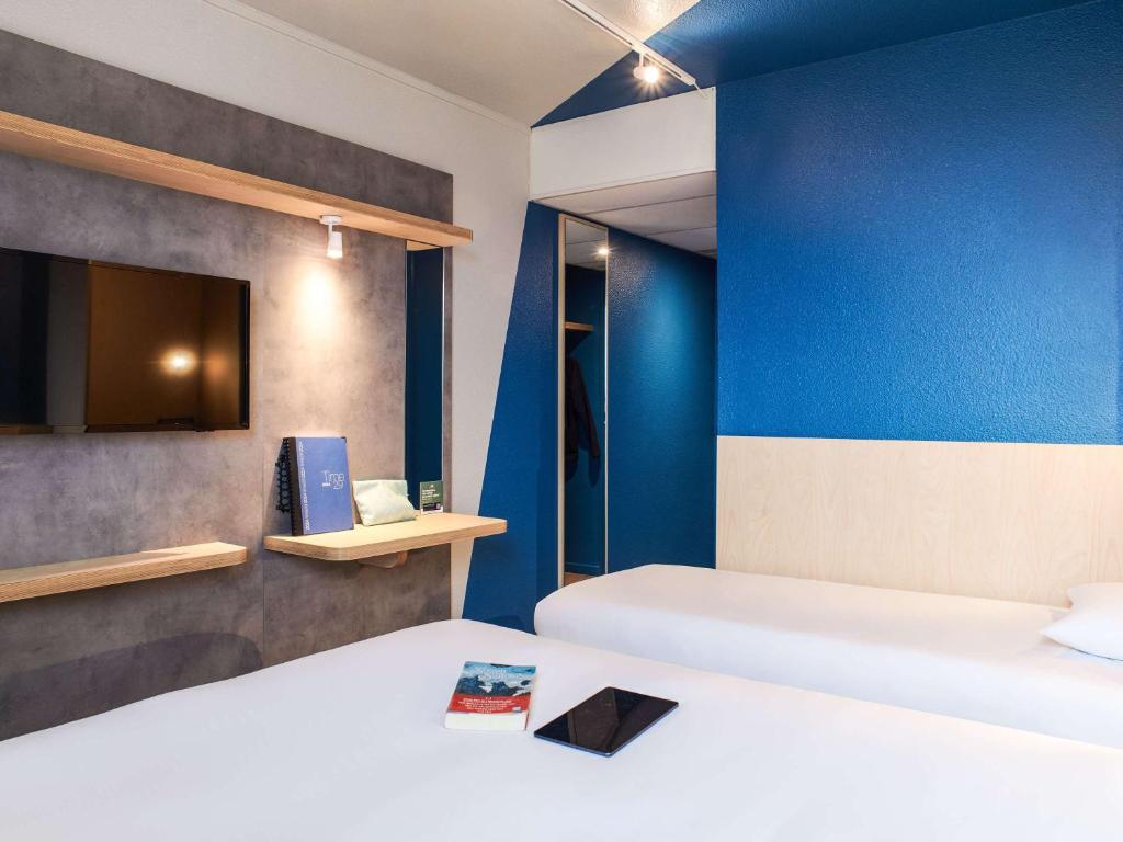CouëronにあるHôtel Ibis Budget Nantes Ouest Atlantis Couëronの青い壁の客室で、ベッド2台が備わります。