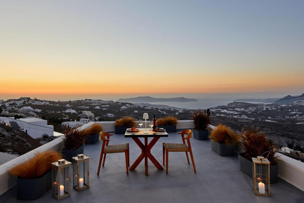 a table and chairs on a balcony with a view at Arxegono Cave Houses Santorini in Pyrgos
