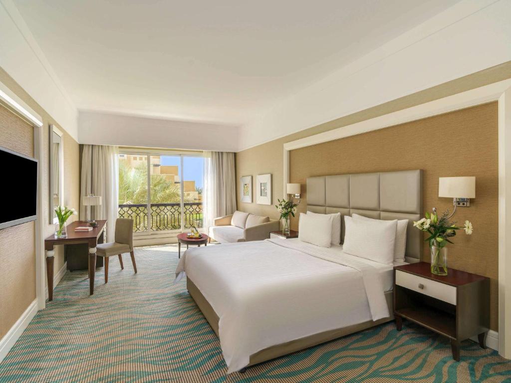 a hotel room with a large bed and a television at Rixos Bab Al Bahr - Ultra All Inclusive in Ras al Khaimah