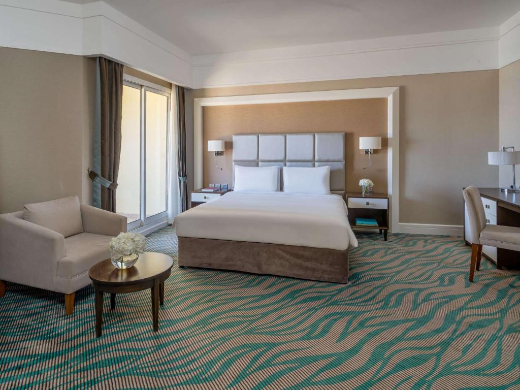 a large hotel room with a bed and a chair at Rixos Bab Al Bahr - Ultra All Inclusive in Ras al Khaimah