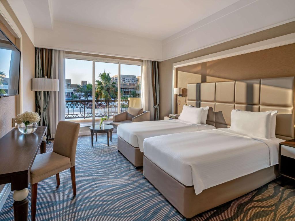 a hotel room with a large bed and a desk at Rixos Bab Al Bahr - Ultra All Inclusive in Ras al Khaimah