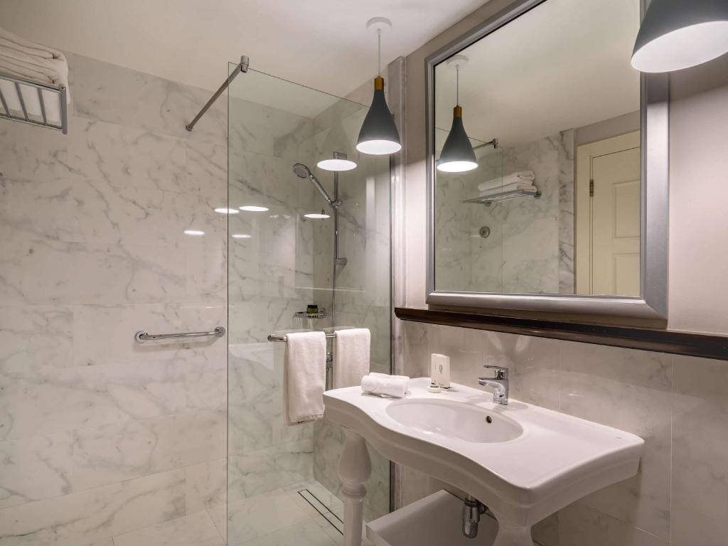 a bathroom with a sink and a glass shower at Rixos Bab Al Bahr - Ultra All Inclusive in Ras al Khaimah