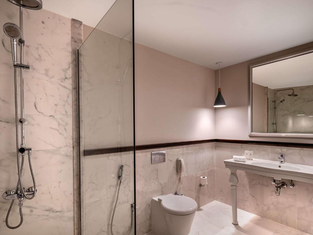 a bathroom with a shower and a toilet and a sink at Rixos Bab Al Bahr - Ultra All Inclusive in Ras al Khaimah