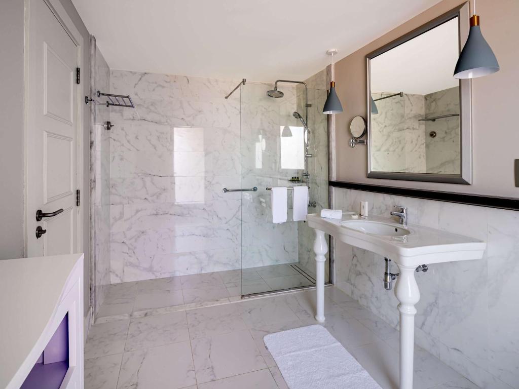 a bathroom with a shower and a sink and a mirror at Rixos Bab Al Bahr - Ultra All Inclusive in Ras al Khaimah