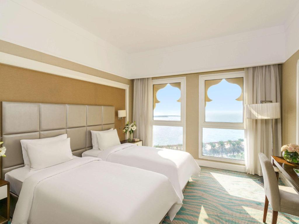 two beds in a hotel room with two windows at Rixos Bab Al Bahr - Ultra All Inclusive in Ras al Khaimah