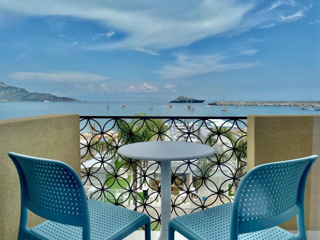 two chairs and a table on a balcony with the ocean at La Finestra sul Mare Modern Apartment in Giardini Naxos