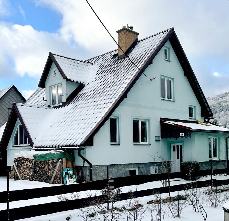 a white house with a black roof in the snow at Apartmama Lipová in Lipova Lazne