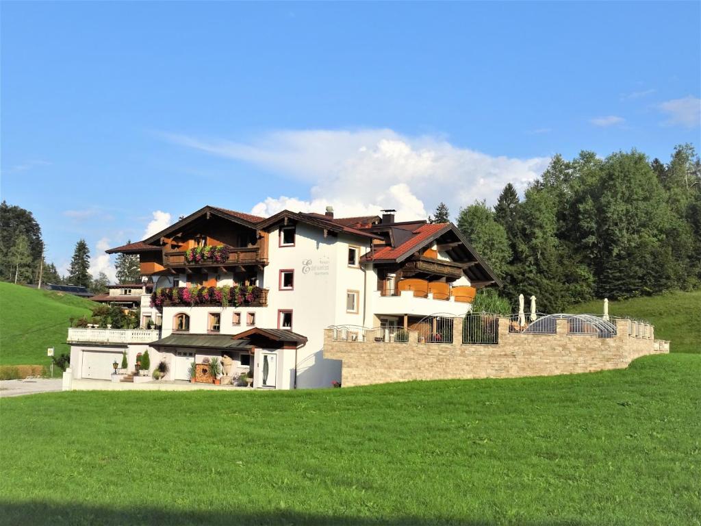 a large white house on top of a green field at Pension Edelweiss in Breitenbach am Inn