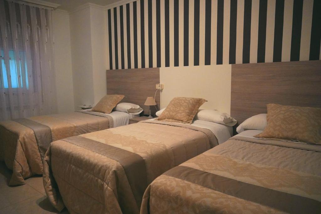 een kamer met drie bedden in een kamer bij Rosende VUT in Arzúa