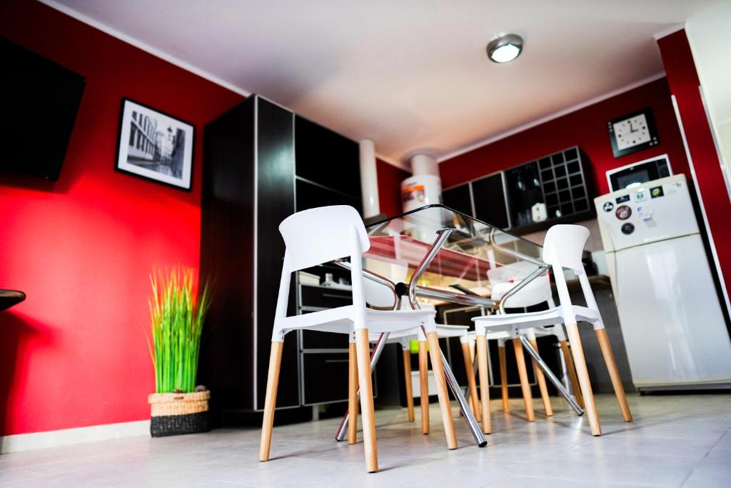 una cocina con 3 sillas blancas y una pared roja en Pueblo Nuevo en Junín