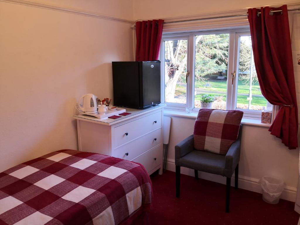 a bedroom with a bed and a tv and a chair at Ashgrove House in Stratford-upon-Avon