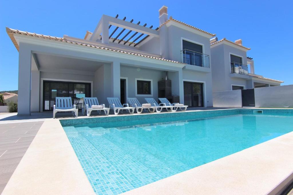 a villa with a swimming pool in front of a house at Villa Goncinha - Piscina in Loulé
