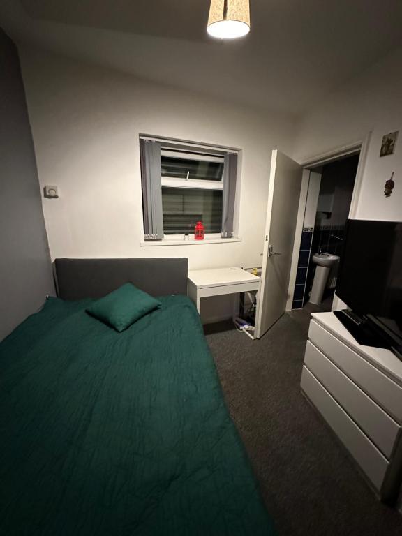 a bedroom with a green bed and a window at Parkside House in Wibsey