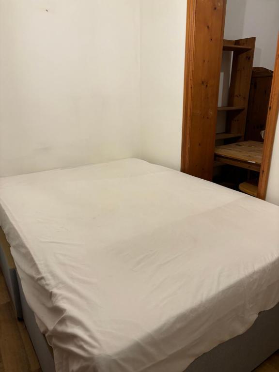 a bed in a room with a white bedsheet at Stay in Islington/Arsenal in London