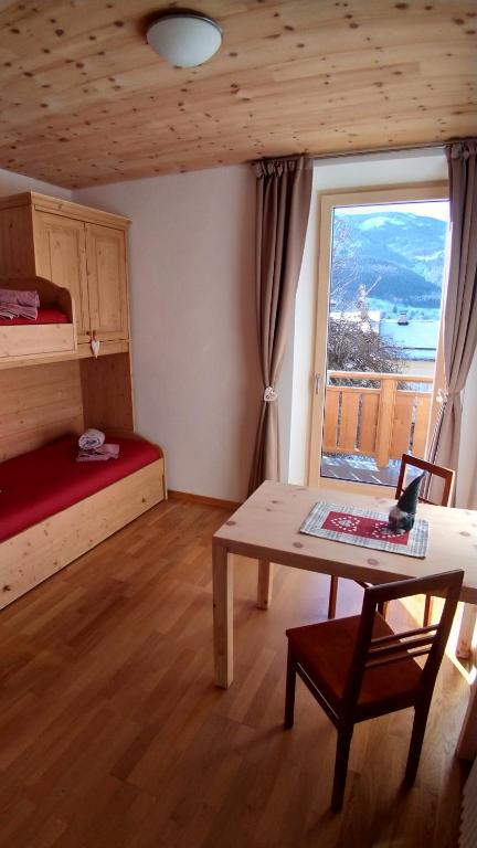 um quarto com uma cama, uma mesa e uma janela em Casa Micéi em Tesero