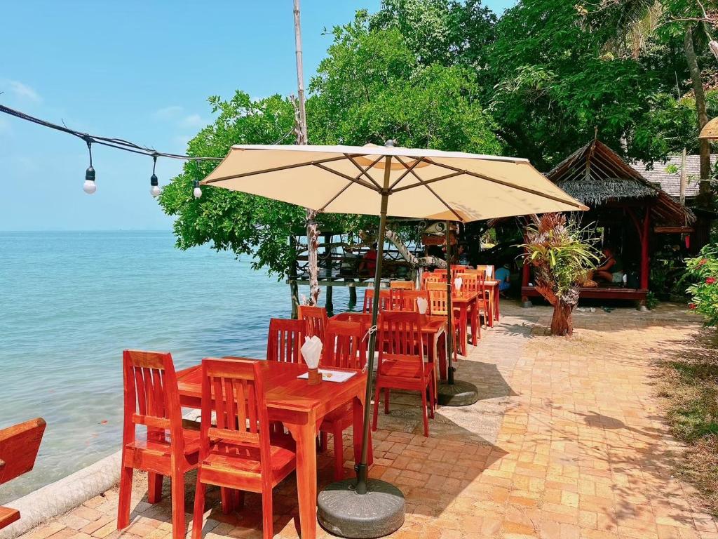 a row of tables and chairs with an umbrella at Sabai Corner Bungalows - SHA Extra Plus in Ko Yao Noi