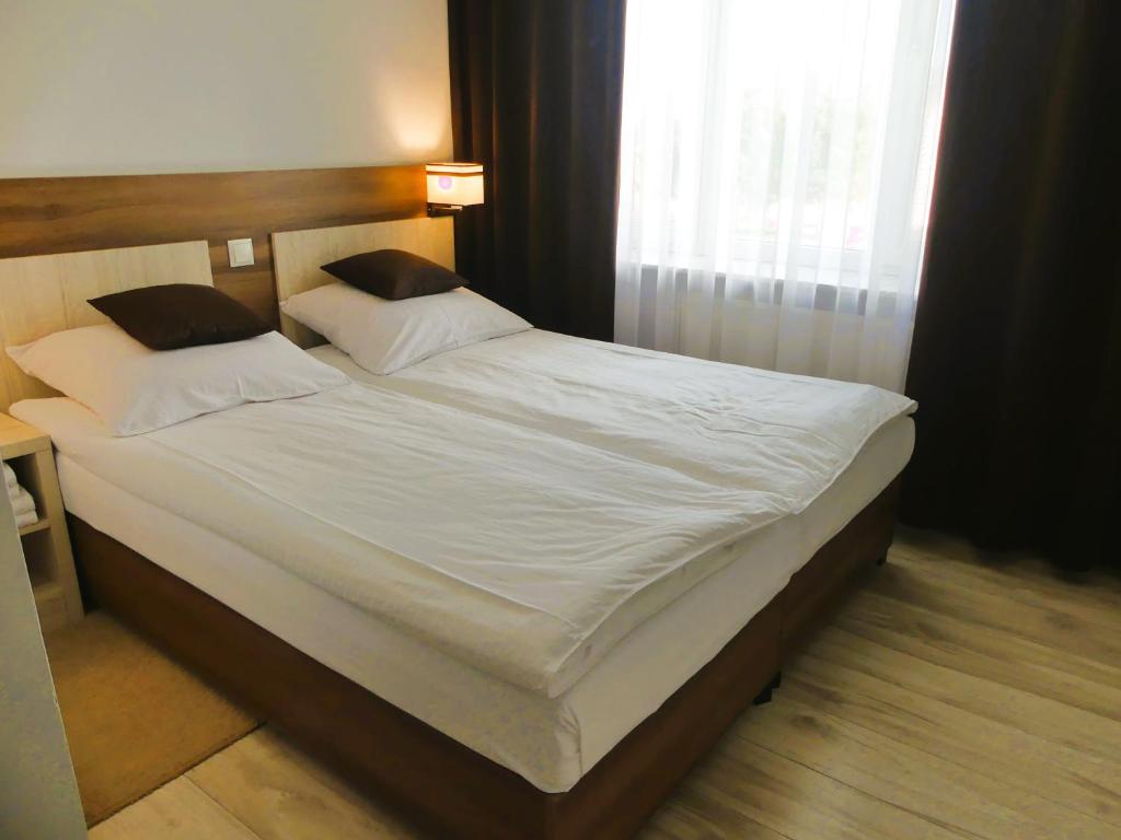 - un lit avec des draps et des oreillers blancs dans une chambre dans l'établissement ZAJAZD SKRZETUSKI, à Wojcieszków