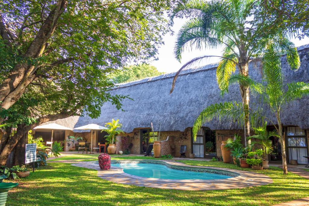 an old house with a swimming pool in the yard at Nguni Lodge in Victoria Falls