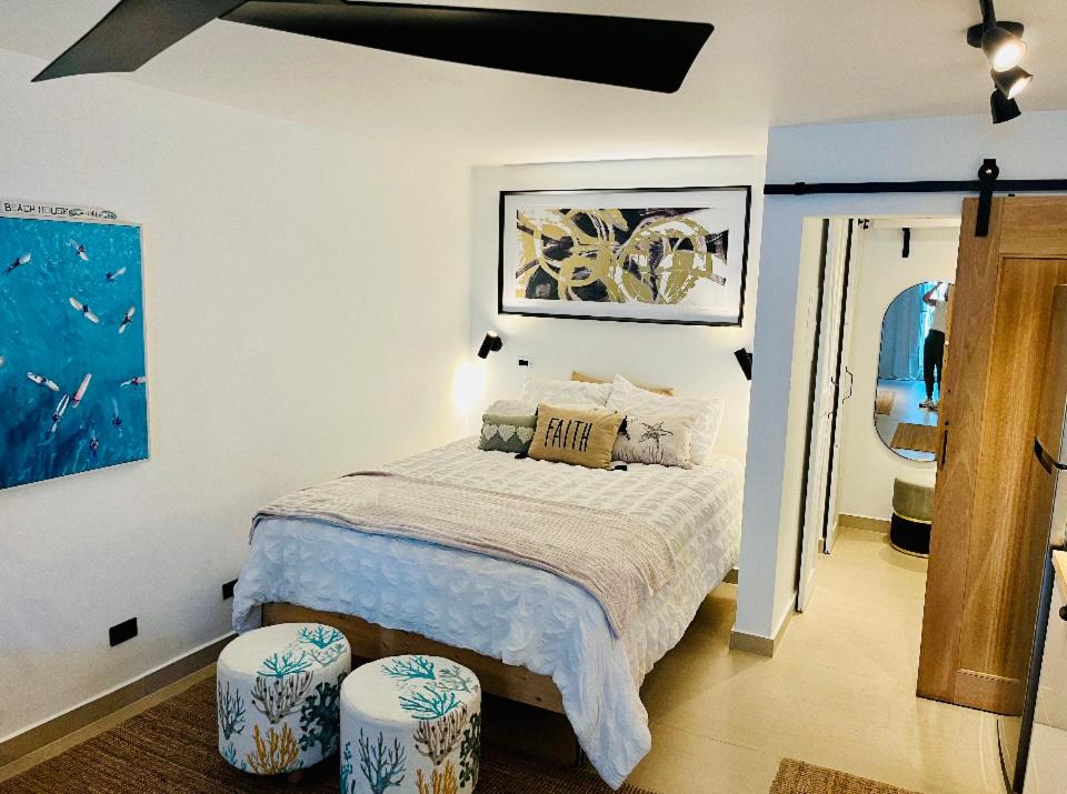 1 dormitorio con 1 cama y 2 taburetes en Isla Verde frente a la playa y Piscina, Céntrico y Accesible en San Juan