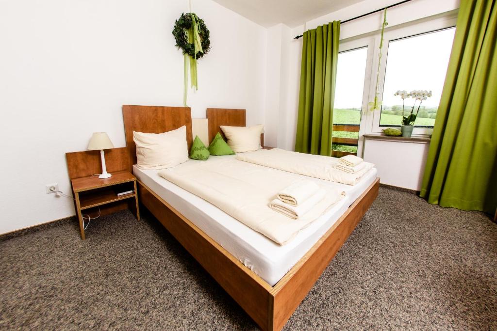 a bedroom with a large bed with green curtains at Landhaus Kopenhagen in Kalletal
