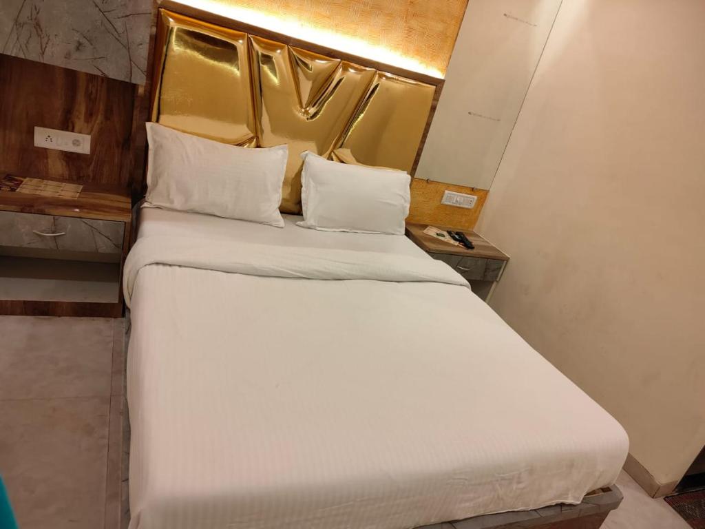 a bed with white sheets and pillows in a room at THE UNITED HOTEL in Mumbai