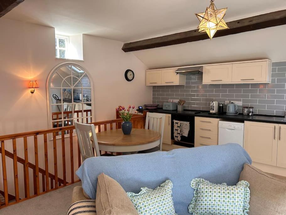a living room with a blue couch and a kitchen at The Old House Barn in Staverton
