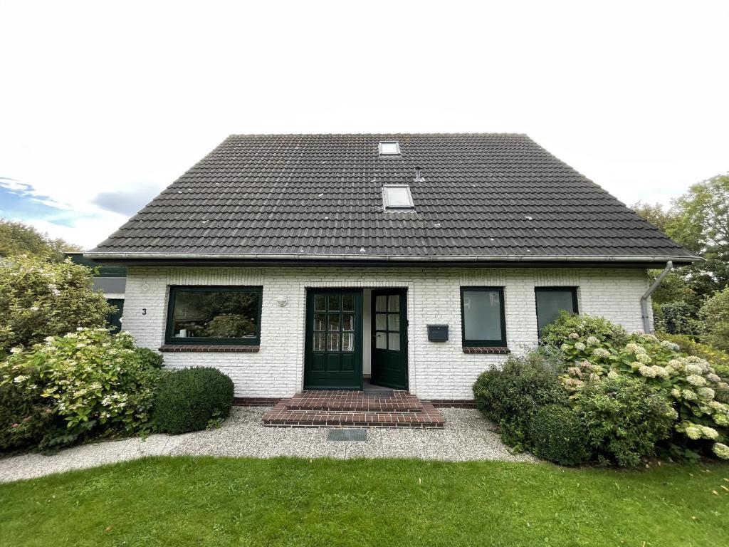 a small white house with a black roof at White House Ferienwohnung 2 in Alkersum