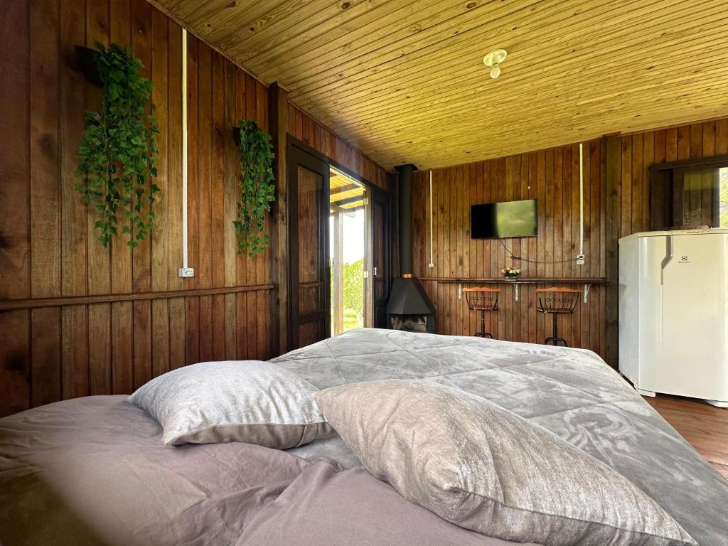 1 cama con 2 almohadas en una habitación con paredes de madera en CABANAS BELVEDERE- SERRA DO RIO Do RASTRO, en Lauro Müller