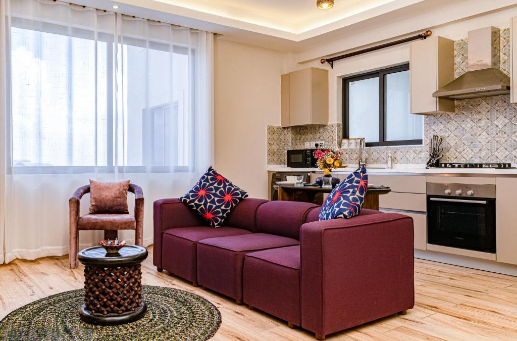 a living room with a purple couch and a kitchen at Elite One Bedroom Apartment,Swimming pool, gym, workspace ,Wonderiss Homes Westland Living in Nairobi