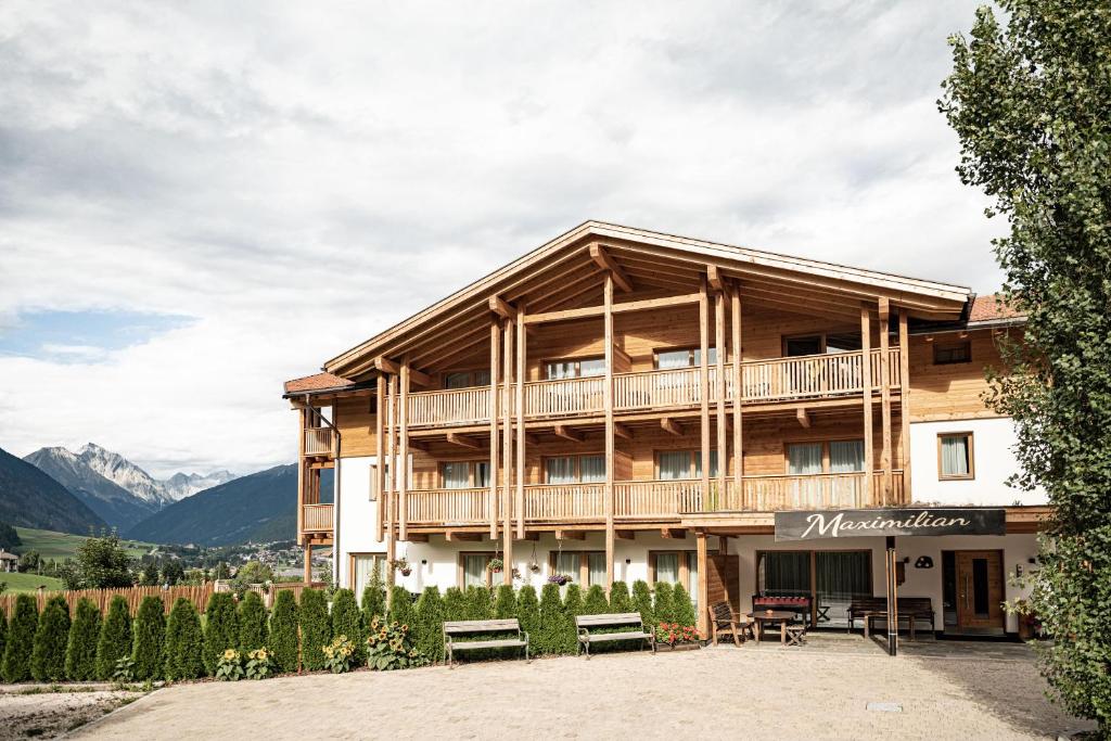 un grande edificio in legno con panchine di fronte di Residence Maximilian a Valdaora