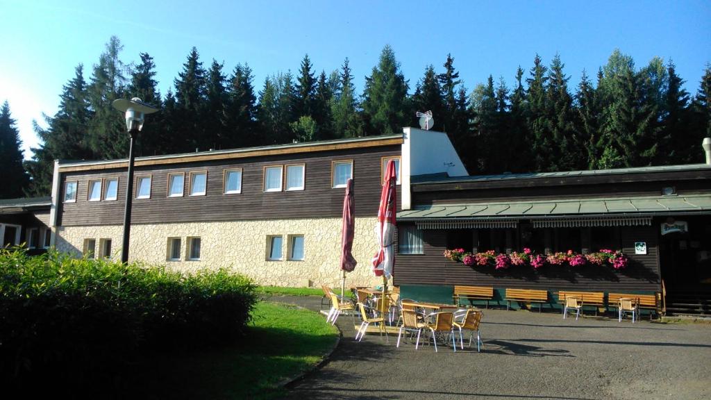 a building with tables and chairs in front of it at Chata Lesanka in Jáchymov