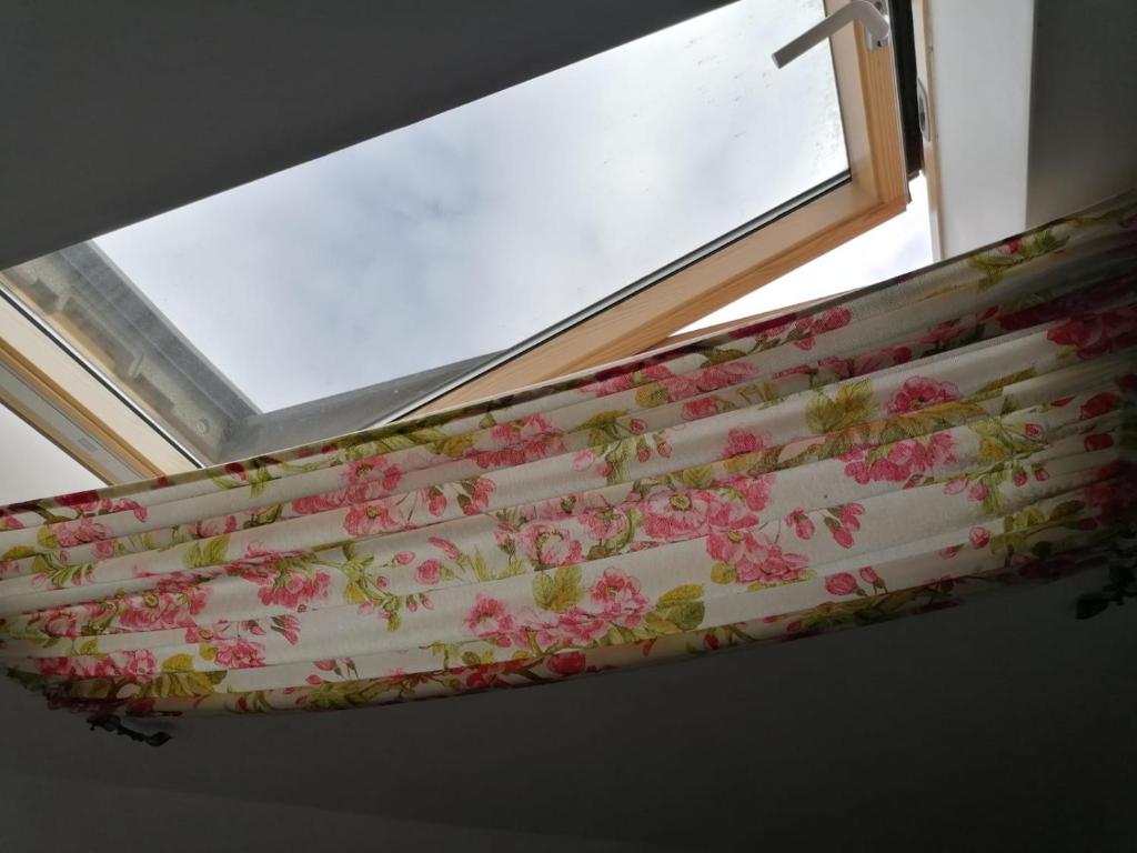 Una ventana con una cortina con flores rosas. en Pensiunea Geostar, en Curtea de Argeş