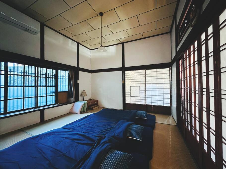 a bedroom with a blue bed in a room with windows at 台中包棟百年日式老宅 請先致電詢問日期 in Taichung