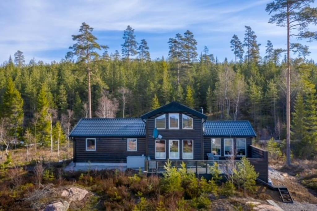 eine Blockhütte im Wald mit Bäumen in der Unterkunft Moderne hytte med badstue in Rømskog
